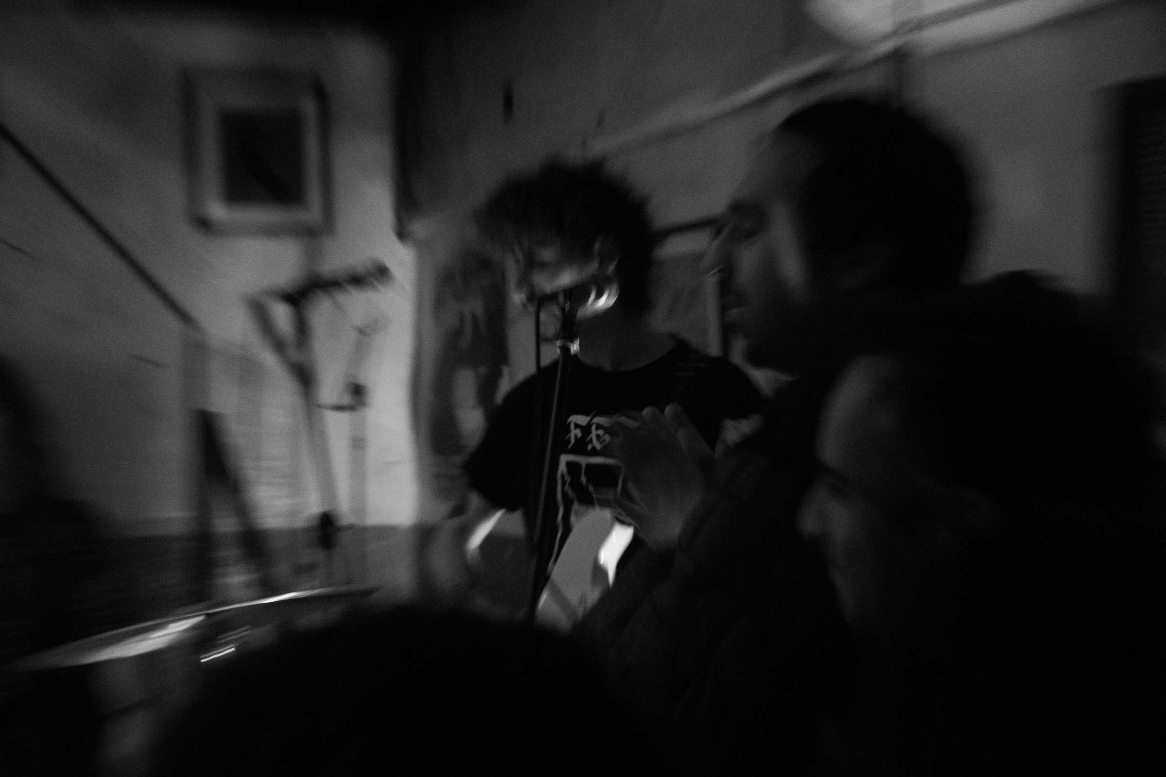 A blurred motion shot of a musician singing into a microphone in a dark basement