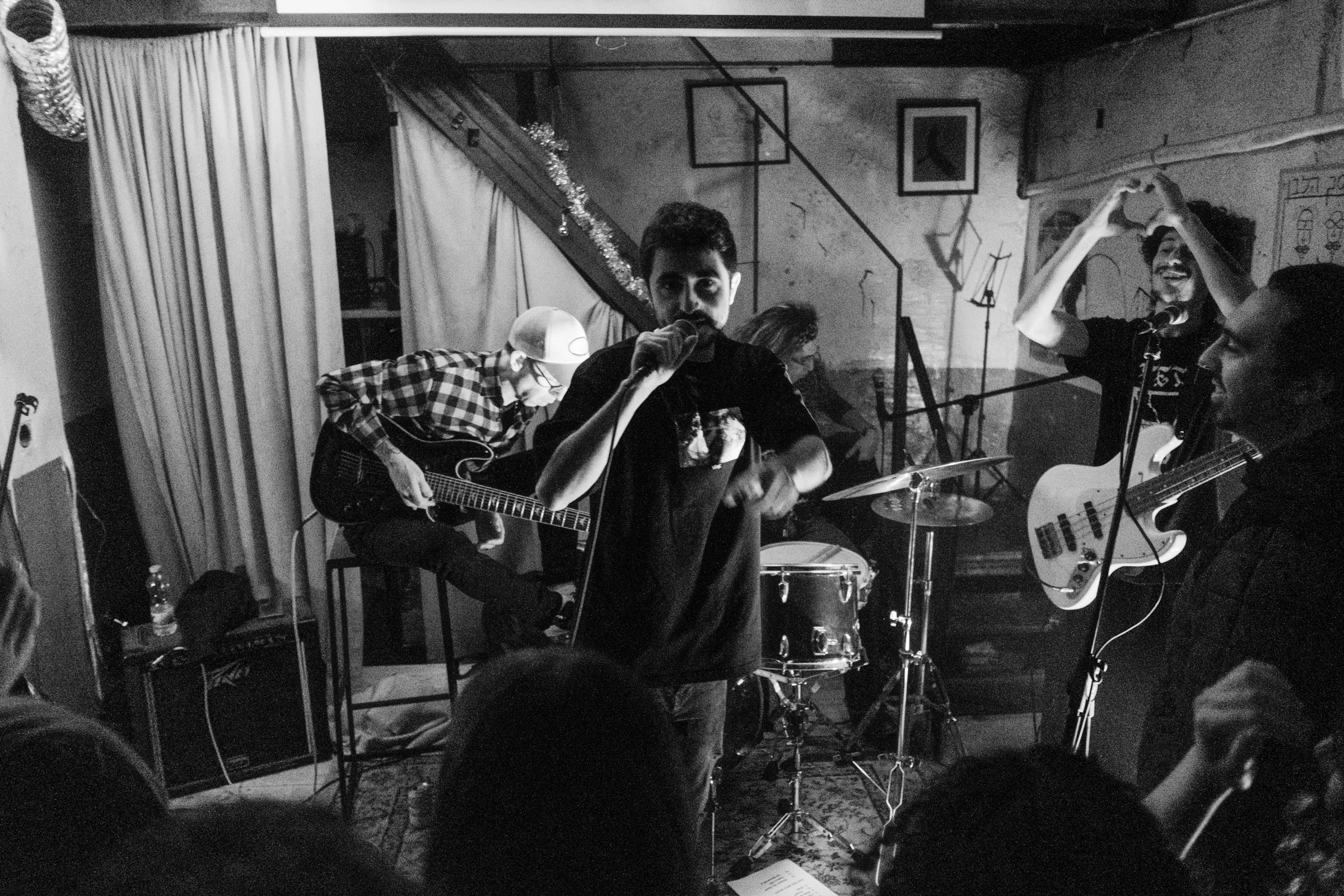 A band performs in a cramped basement venue, musicians crowding together with guitars and drums