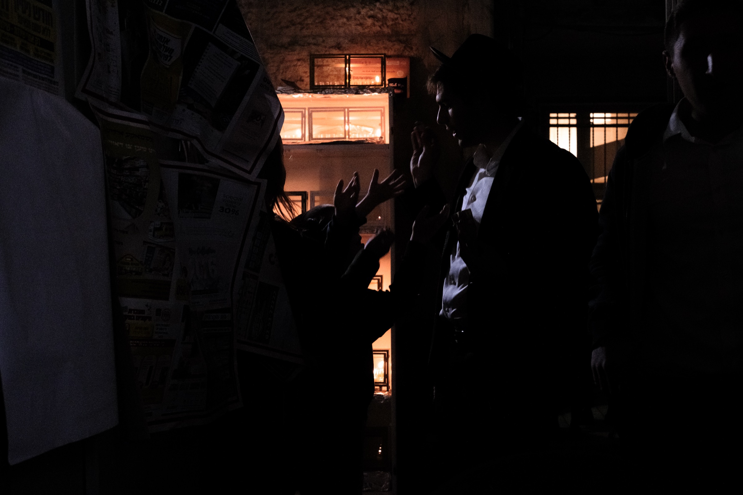 Children's hands reach toward a parent asking for Dmei Hanukkah in a dark alley